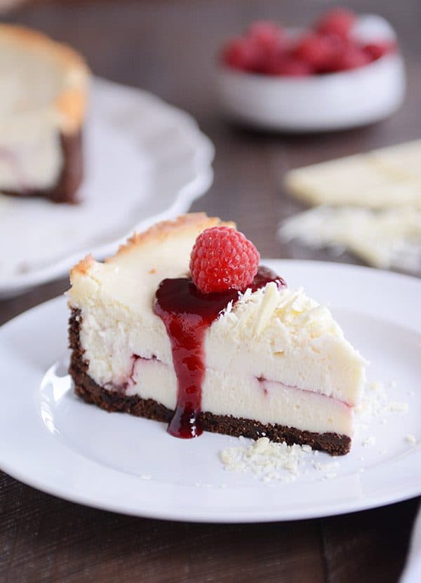 A slice of white chocolate raspberry cheesecake on a white plate. 