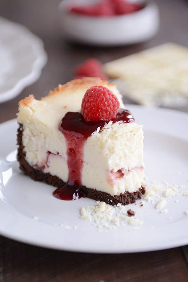 A slice of white chocolate raspberry cheesecake with a bite taken out. 