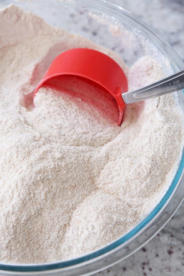 Scooping whole wheat flour out of bowl.