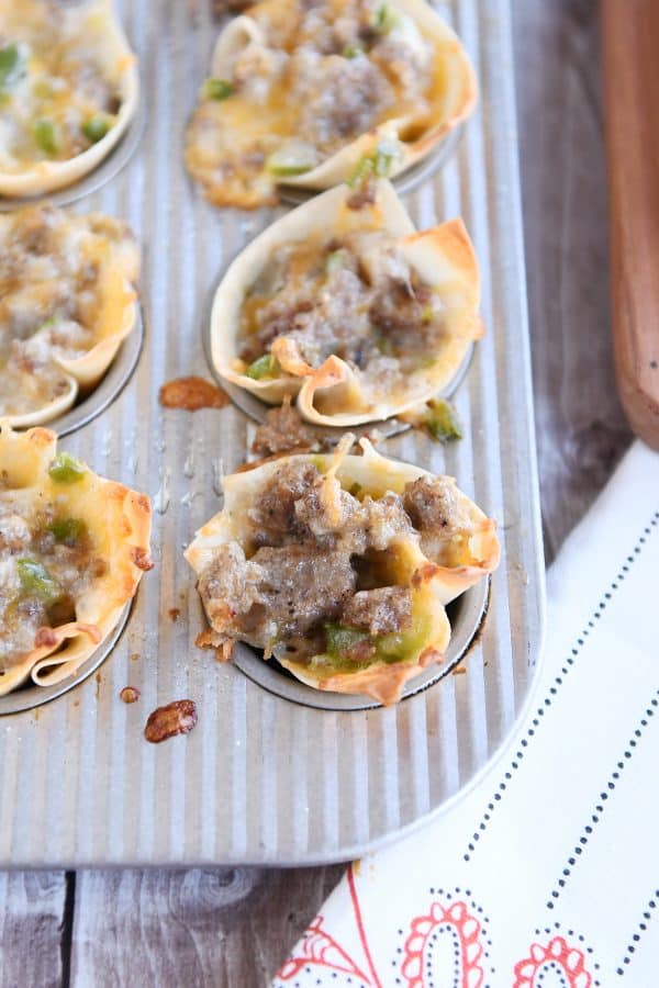 Mini muffin tin filled with wontons, sausage, cheese and green peppers.