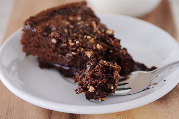 A slice of fudgy chocolate cake with a bite being taken out.