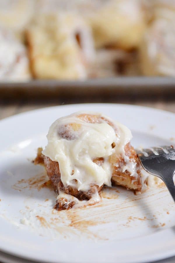 A mostly eaten cinnamon roll on a white plate. 