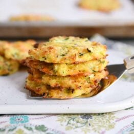 Cheesy baked zucchini bites stacked on a spatula.