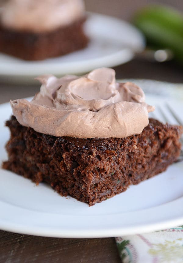 A piece of chocolate cake with a large dollop of whipped chocolate frosting on top.