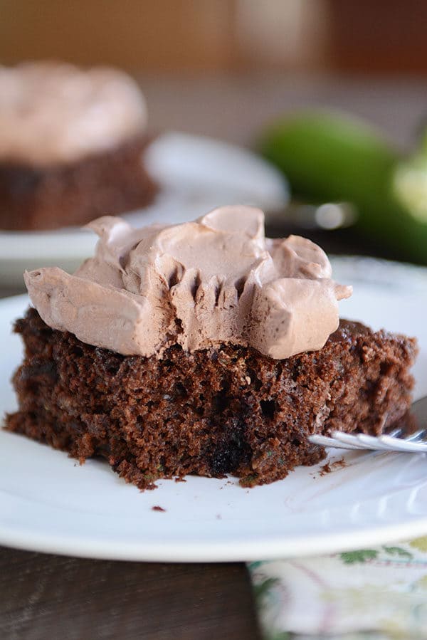 A piece of chocolate cake with a bite taken out and chocolate whipped frosting on top.