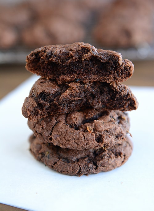 Chocolate zucchini cookies stacked on top of each other with the top two with a bite taken out.