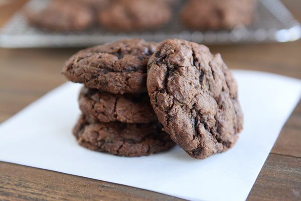 Four chocolate zucchini cookies on a sheet of parchment.
