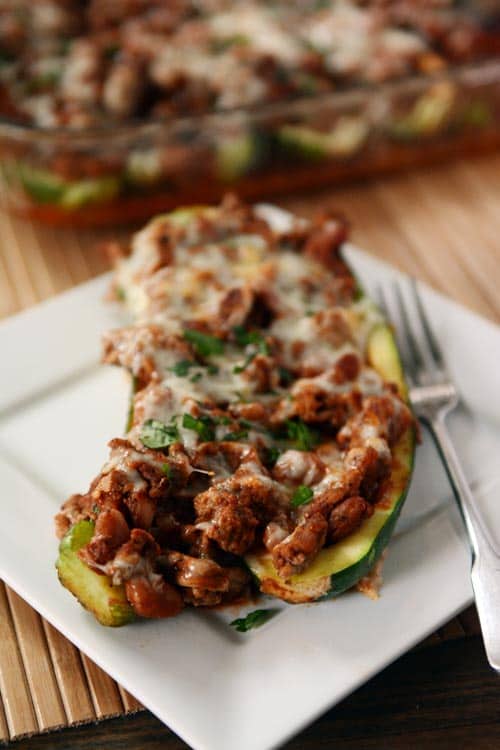 a cooked meat and cheese stuffed zucchini on a white plate